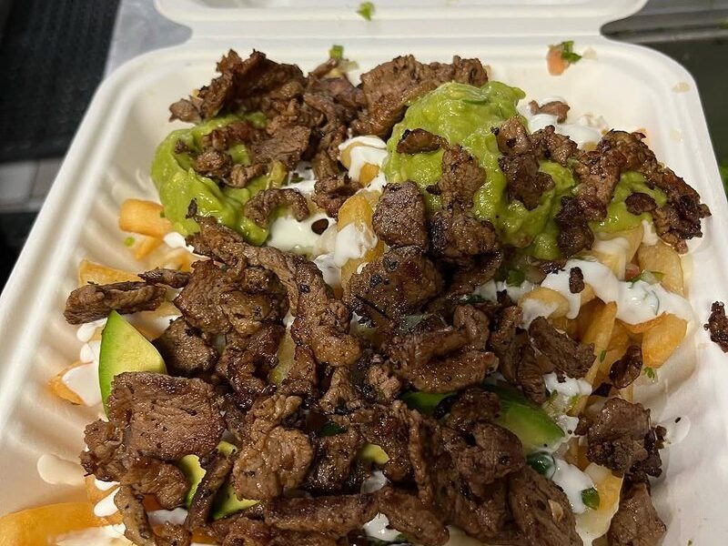 Maria's Tacos asada fries piled with grilled steak, guacamole, sour cream and avocado in a takeout box