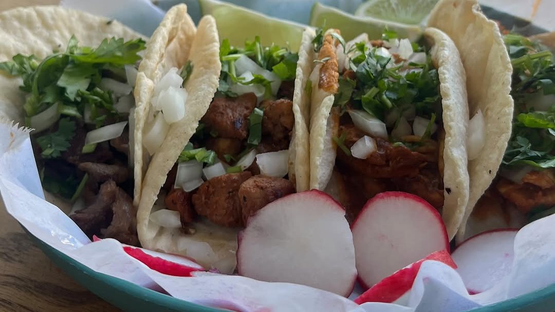 Street tacos on Maria's Tacos homemade tortillas with onion, cilantro, lime and radish, on a table by the front window